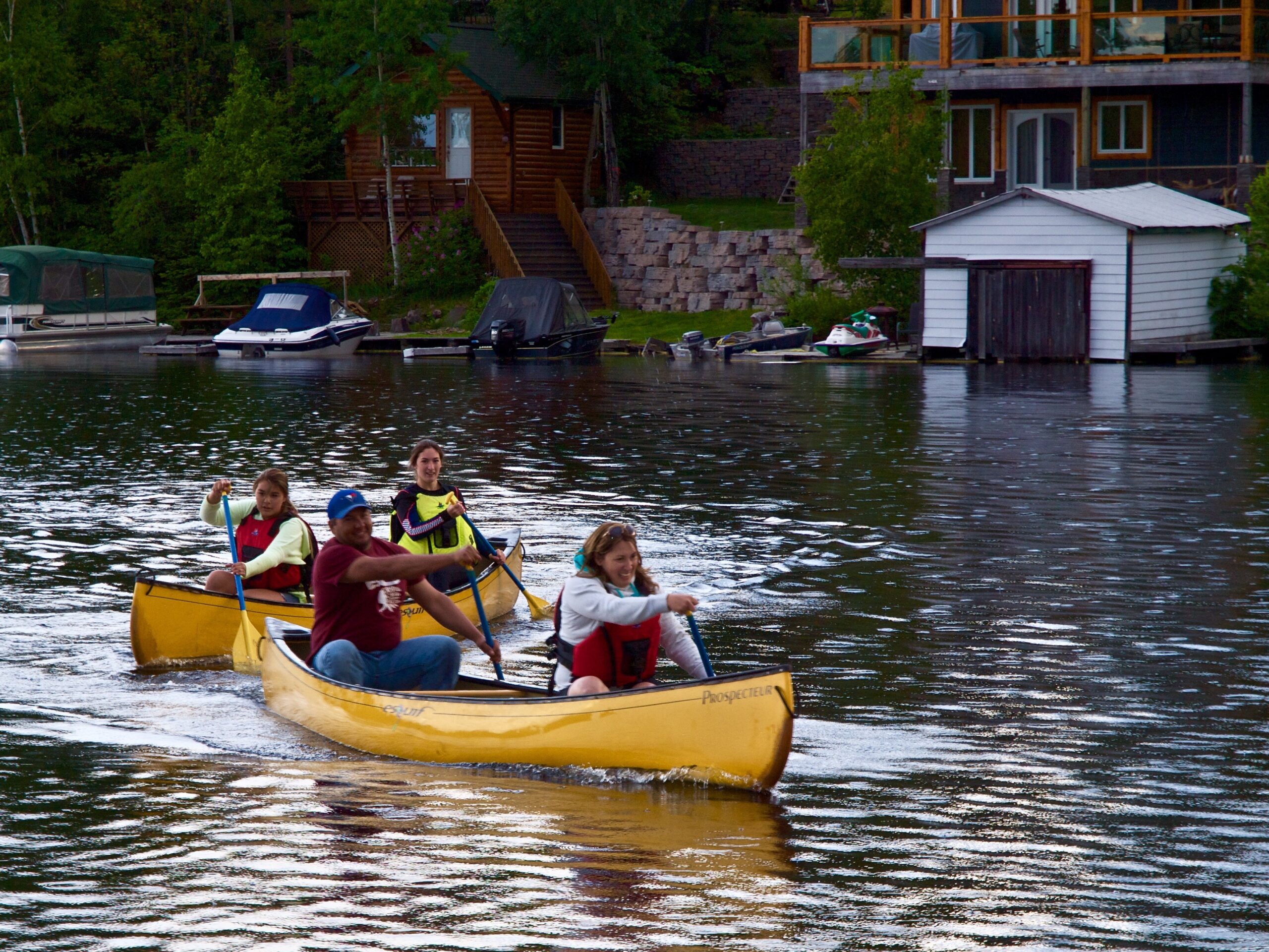 OLYMPUS DIGITAL CAMERA Two canoes with two recreational paddlers in each boat smiling and enjoying a day of fun on Lake Kipawa.