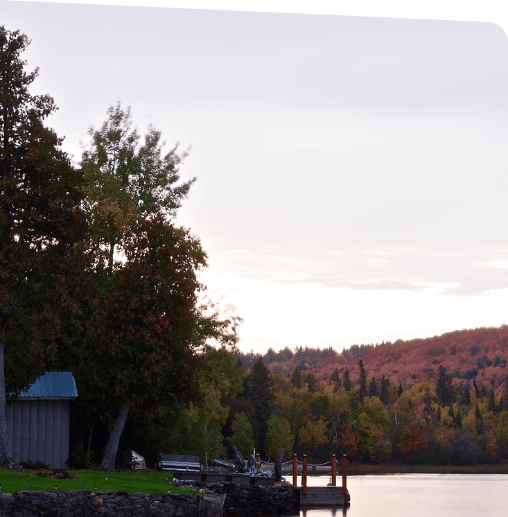 An early morning view of a peaceful private dock on Lake Kipawa with a background of orange and yellow leaved trees.