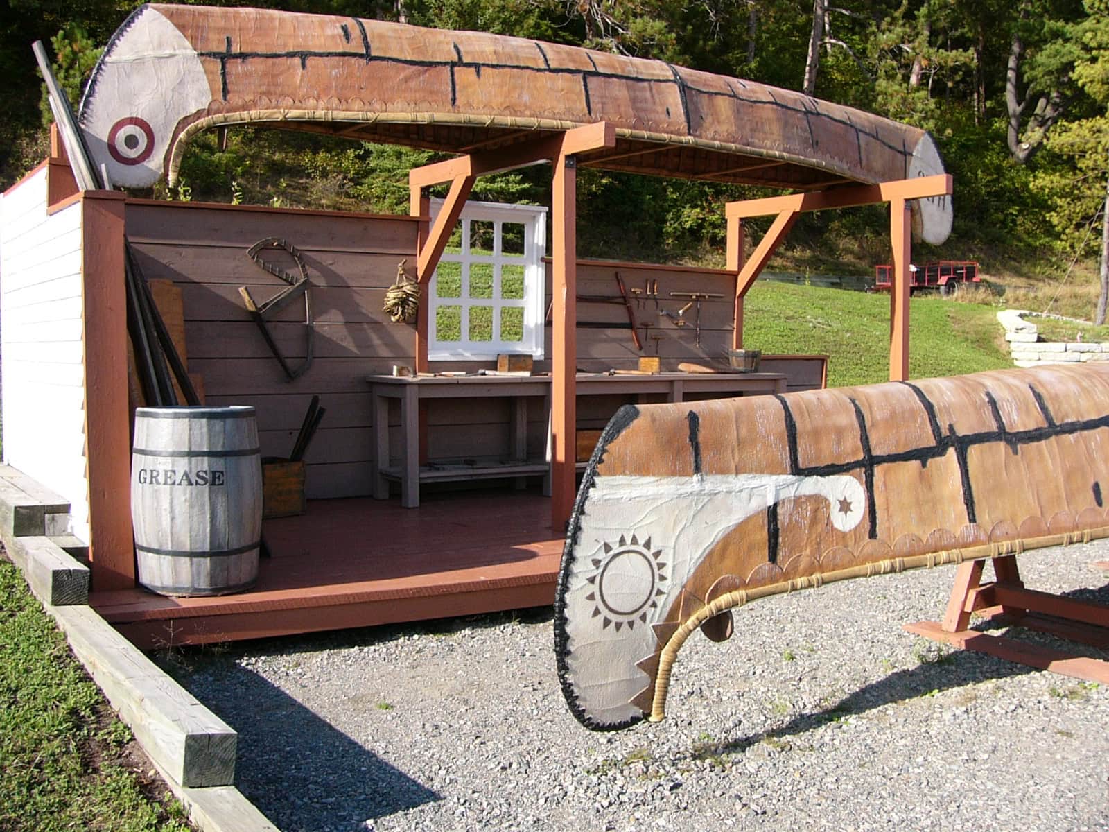 A photo of an exhibit at Fort Témiscamingue, featuring two canoes on display in what appears to be a canoe-making workshop setting.